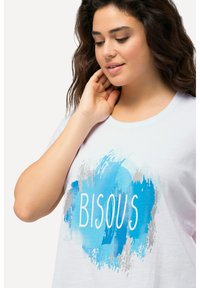 Camiseta blanca de manga corta con un gráfico de salpicadura de acuarela azul y el texto "BISOU" en blanco. Material de algodón suave con un escote redondo.