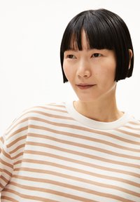 Gestreifter beiger und weißer Sweatshirt mit rundem Halsausschnitt, das einen leicht lockeren Schnitt und eine weiche Textur aufweist. Kurze Ärmel, lässiges Design.