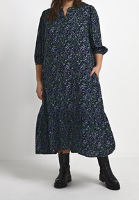 Lång blommig klänning med marinblå bakgrund och blommor i blått och grönt. Lätt tyg, lös passform, med v-ringning och trekvartsärmar.
