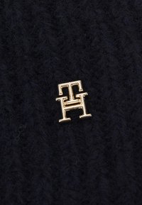 Tessuto a maglia blu navy con una finitura testurizzata e caratterizzato da un accento logo in tono oro di lettere intrecciate "T" e "H".