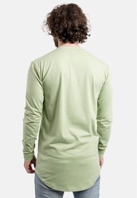 Lange mouwen shirt van lichtgroene katoen, met een afgeronde zoom, aansluitende mouwen en een subtiel logo geborduurd nabij de halslijn.