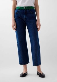 Pantaloni in denim blu con una vita a fantasia verde, taglio dritto, tasche frontali e chiusura con bottone. Stile classico e textured.
