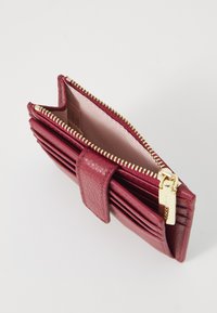 Portafoglio in pelle rossa texture con chiusura lampo dorata e bottone a pressione. Contiene più scomparti per carte e una fodera interna liscia.