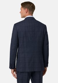 Tumši zila kvadrātveida svārku jakas, kas izgatavota no teksturēta materiāla, ar vienu atveri, strukturētām plecu daļām un pogu aprocēm. Šūta piegriezuma.