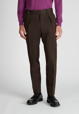Braune maßgeschneiderte Hosen mit glatter Textur, Frontfalten und doppelter Knopfverschluss, kombiniert mit schwarzen Loafers.