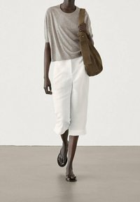 Harmaa lyhytsiipiäinen paita, valkoiset lyhyet housut sivuaukkoineen ja mustat flip-flopit; kantaa ruskeaa mokkakuosisella olkalaukulla. Yksinkertainen muotoilu.