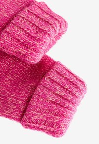 Tissu tricoté rose avec un motif texturé. Les poignets présentent un design côtelé d'une teinte rose plus foncée, renforçant la chaleur et le style.