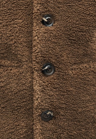 Καφέ παλτό από φλις με υφή, πέντε μαύρα κουμπιά και κλασικό γιακά. Εντυπωσιακές λεπτομέρειες περιλαμβάνουν απαλή επιφάνεια.