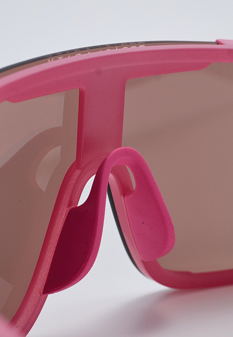 Różowe plastikowe okulary przeciwsłoneczne o błyszczącym wykończeniu, brązowe szkła przyciemniane oraz elastyczny design noska dla wygody.