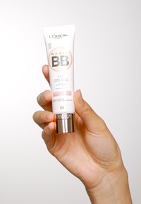 L'Oréal Paris Magic BB-kräm i en vit tub med roséguldiga detaljer, märkt "5 i 1" för hudperfektion, hålls i en hand.