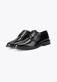 Scarpe oxford in pelle nera con finitura lucida, punta arrotondata e quattro occhielli per i lacci; presentano un tacco leggermente rialzato.