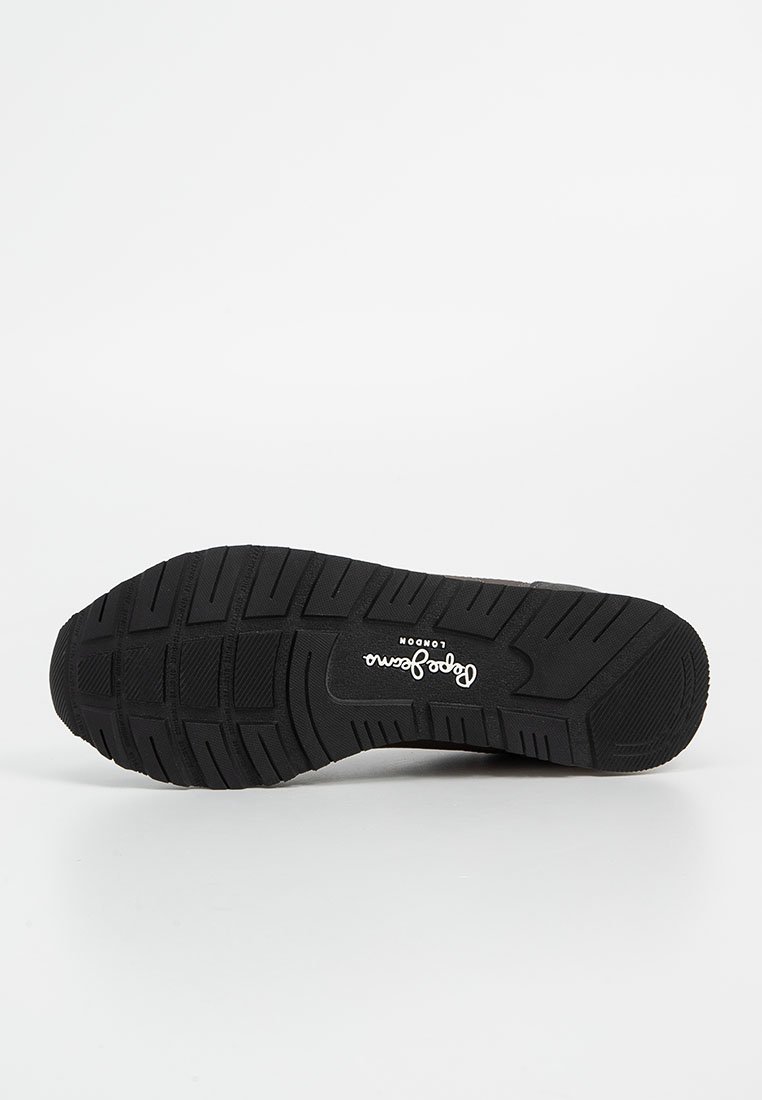 Suela de zapato de goma negra con patrón de agarre texturizado; presenta el logo de la marca en blanco. Diseño sencillo y funcional, hecho para la durabilidad y la tracción.