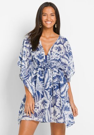 Abito floreale con scollatura a V profonda, maniche corte e vita elastica. Presenta uno sfondo blu con motivi di ibisco e foglie bianchi.