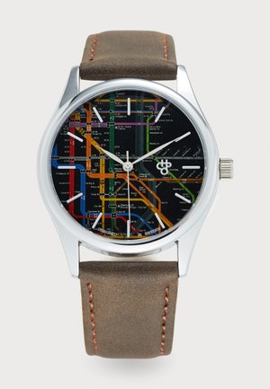 Rund klokke med et sølvfarget metallhus, svart skjerm med et fargerikt t-banesystemkart-design, og en brun lærrem med oransje søm.