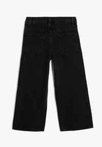 Jean noir à jambes larges en denim, avec deux poches arrière, passants de ceinture et un ourlet propre. Le tissu a une texture douce et robuste.