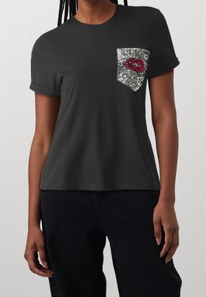 Zwart T-shirt met korte mouwen, opgerolde manchetten en een zilveren pailletten zakje met rode pailletten lippen op de linkerborst.