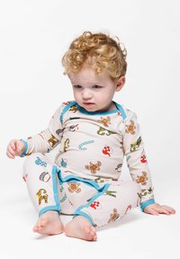 Long-sleeve, cream pajama set with blue trim, featuring patterns of gingerbread men, candy canes, and holiday motifs. Soft fabric and playful design.
