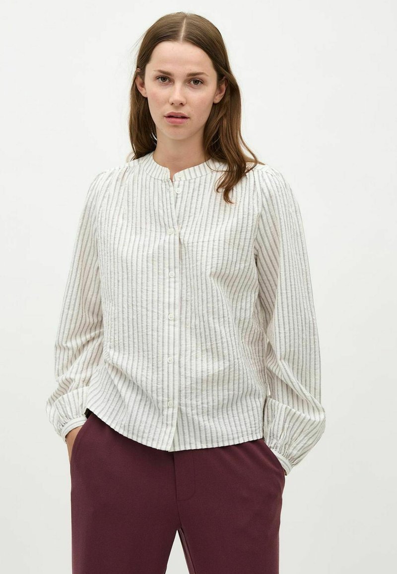 Hvidstribet skjorte med knapper, rund halsudskæring, lange puffede ærmer og et tekstureret stof. Kombineret med burgundy bukser.
