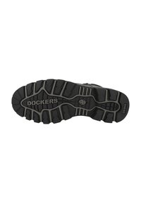 Suela de goma negra con surcos y hendiduras profundas, con la marca "DOCKERS" en el centro y "D5SHX" en el lado para mayor tracción.