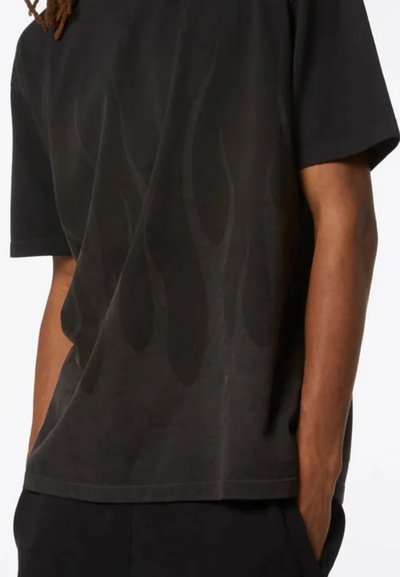 T-shirt nera a maniche corte con un motivo di fiamme sottile in una tonalità più scura. Realizzata in tessuto morbido con una vestibilità ampia e scollatura rotonda.