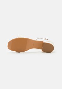 Beige sandaler med chunky hæl, designet med en glat overdel, justerbar rem og en tekstureret gummisål for godt greb.