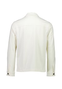 Vitt bomullskjol med långa ärmar, kragliknande hals och svarta knappar på ärmsluten. Slät textur och enkel design, bakvy.