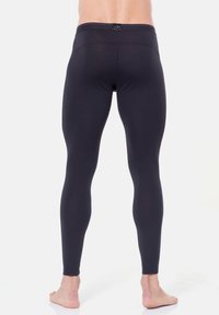 Schwarze Leggings mit glatter Textur, hohem Bund und figurbetontem Design. Merkmale sind ein kleines Markenlogo auf der Rückseite.