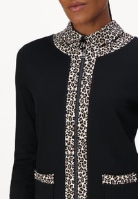 Schwarze Zip-up-Jacke mit Kragen und Taschenakzenten aus Leopardenmuster, aus strukturiertem Stoff mit taillierter Passform.