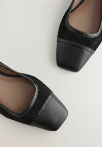Stivali neri con una tomaia in suede testurizzato e punta in pelle. Design a punta quadrata e finitura lucida sull'accento in pelle nera.