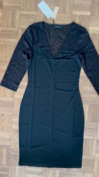 Svart kjole med blonde lange ermer og V-hals. Jevnt stoff, tettsittende design og knelengde. Merkeetikett synlig.