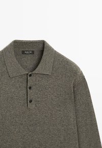 Tmavě šedé polo tričko z měkké pletené látky s límečkem a třemi černými knoflíky. Má strukturovaný povrch a dlouhé rukávy.