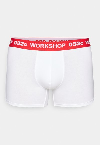 Weiße Baumwoll-Boxershorts mit einem roten elastischen Taillenbund, auf dem "WORKSHOP 032c" in Weiß gedruckt ist. Glatte Textur und enganliegender Schnitt.