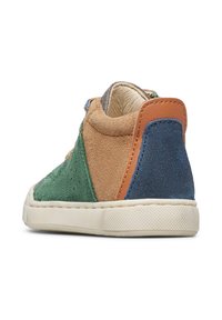 Sneaker per bambini con pannelli in suede verde, tan, blu e marrone e suola in gomma bianca, vista da un angolo posteriore su sfondo bianco.