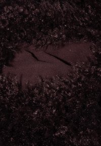 Brązowa tkanina z sztucznego futra o miękkiej, puszystej strukturze i różnorodnych włóknach, z gładką sekcją kontrastującą z otaczającą teksturą.