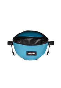 Sacchetto di stoffa blu con interno nero, forma rotonda, chiusura con coulisse e un'etichetta del marchio Eastpak all'esterno. Presenta una texture liscia.