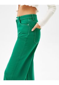 Gröna vida jeans i bomull med hög midja, sidofickor och kontrasterande sömmar. Slätt, strukturerat tyg.