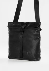 Borsa a tracolla nera, rettangolare, realizzata in materiale sintetico liscio, con patta pieghevole, tracolla regolabile e logo in rilievo.