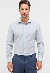 Camicia a righe blu chiaro e bianca, con maniche lunghe, colletto classico e design slim fit. Abbinata a pantaloni blu navy.