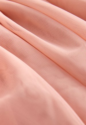 Růžová texturovaná tkanina zobrazená ve skladech, odhalující prodyšnou síťovou strukturu a hladký vzhled.