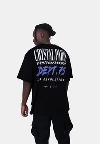 Černé oversize tričko s výrazným bílým a modrým textem na zádech. Pohodlný materiál a volný střih pro snadné nošení.