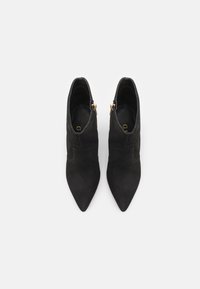 Bottines en daim noir avec des orteils pointus, dotées d'une fermeture éclair sur le côté et d'une texture lisse, présentées de dessus.