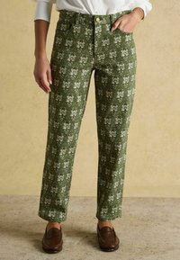 Zelené nohavice so vzorom kvetín, rovný strih, päť vreciek a jemný lesk, v kombinácii s hnedými mokasínami.