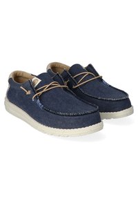 Marineblaue Canvas-Schuhe mit hellbeigen Akzenten, runder Spitze, dünnen Schnürsenkeln und einer strukturierten Gummisohle mit einem genähten Muster.