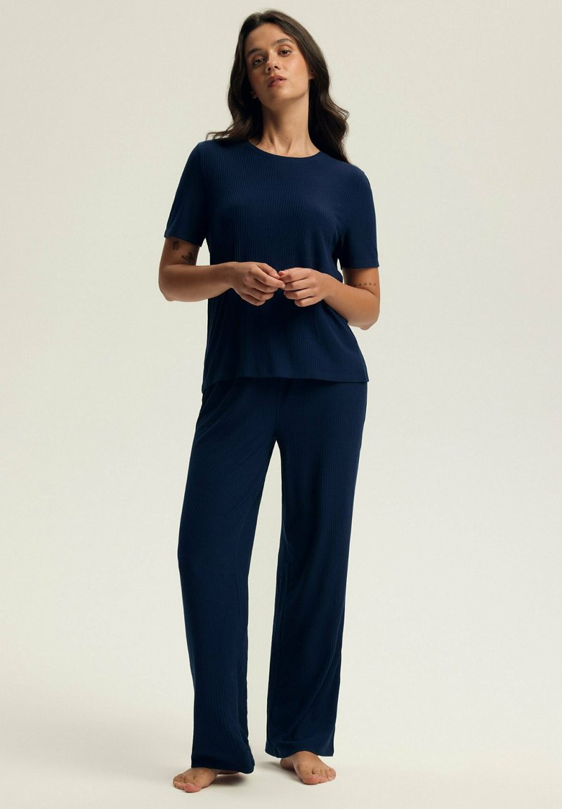 Granatowy, żeberkowy zestaw odzieży do wypoczynku, składający się z koszulki z krótkim rękawem i długich spodni. Miękka tekstura i luźny krój dla wygody.