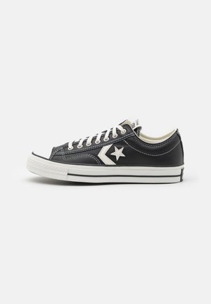 Tenisi negri, de tip low-top, din canvas, cu sireturi albe, talpă din cauciuc și un logo alb în formă de stea pe lateral. Au detalii cusute.