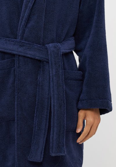 Accappatoio in spugna blu navy con colletto sciallato, vita con nastro e due tasche frontali. Tessuto morbido e maniche lunghe.