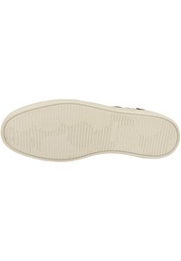 Suela de un zapato con una superficie texturizada; presenta ranuras horizontales y verticales, patrones circulares y una marca en relieve. El color es beige.