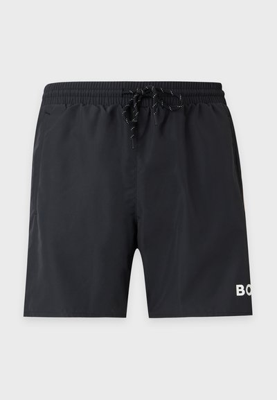 Short de bain noir à taille élastique avec cordon et logo texte blanc partiel sur la jambe gauche sur un fond uni.