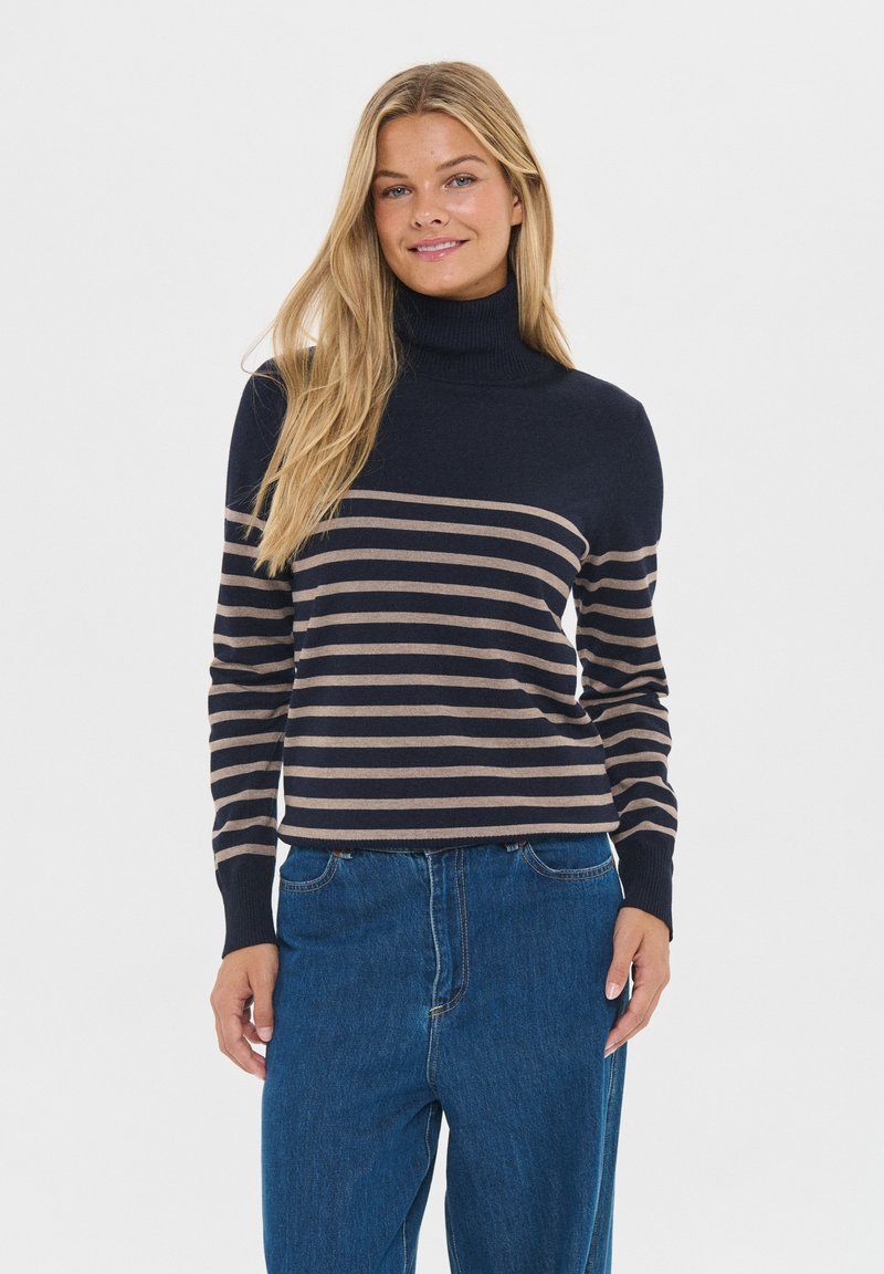 Sweter w paski w kolorze granatowym i beżowym z wysokim kołnierzem oraz ściągaczami, zestawiony z luźnymi niebieskimi dżinsami. Gładka tekstura, casualowy fason.