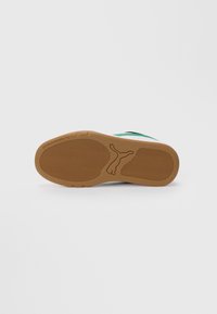Såle av en sneaker med brun gummibelegg, Puma-logo i midten og teksten "See you at the park" nær tåpartiet.